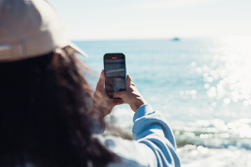 a young girl takes a selfie on her phone on the seashore. happy girl calling via video chat on the...