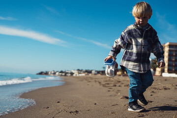 Toddler on vacation. Boy plays with a toy car on the seashore. boy 3-yers old playing on the...