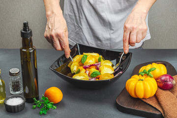 A woman is preparing a tomato salad. Ripe vegetables, herbs, aromatic spices, olive oil