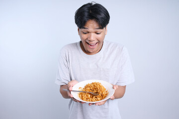 Excited Young Asian Man Showing a Plate of Delicious Noodles Isolated on White Background 