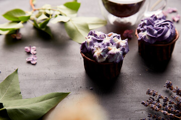 Floral purple cupcakes using trend Dreamy Escapism. Desserts and flowers background. Aesthetics food