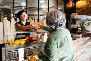 Woman Handing Bowl of Food to Another Woman