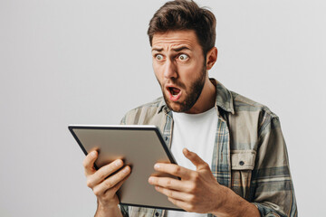 man holding a tablet and looking shocked on a white background