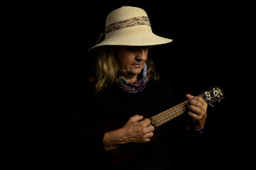 older woman alone playing ukulele