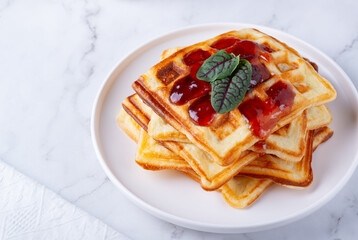 Belgian waffles with strawberry jam on a white background