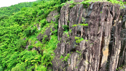 Scenic Serenity: A drone gracefully soars over rugged cliffs, embraced by lush tropical rainforests. Nature's beauty revealed from above. Thailand.

