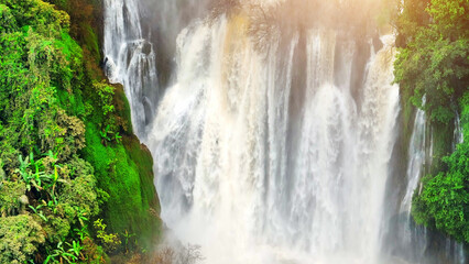 A bird's-eye perspective, a sprawling waterfall, shrouded within a thriving tropical rainforest,...