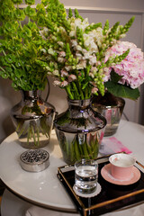 bouquets of flowers are on the table, a tray with a cup and a glass of water