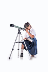 Isolated little Indian asian schoolgirl in school uniform looking into a telescope.