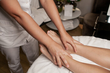 Obraz na płótnie Canvas Massage therapist doing foot and leg massage with hands