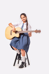 Indian asian school kid girl playing guitar against white background