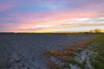 Beautiful pink sunset over a barren and plowed land