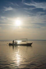 Obraz premium A boat's silhouette glides through the waters of the Albufera Natural Park lagoon in Valencia, Spain, at sunset.