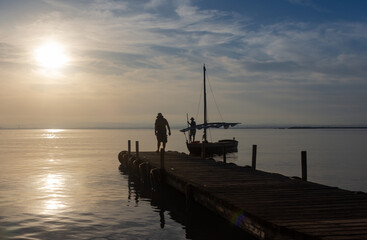 A fishing boat arrives at the pier of the Albufera lake port at sunset