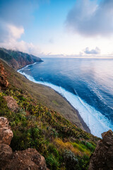 View of rough ocean with waves, volcanic beach, sunset over a huge cliff  in Lighthouse Ponta do...