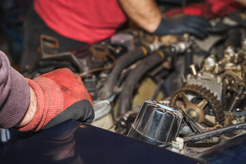 Car mechanic's hand in protective gloves at the open hood. Car repairing. Auto service. Maintenance.