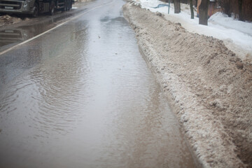 Snow is melting on the road. Puddle in spring. Highway in the water. Melting snow on the highway in the city.