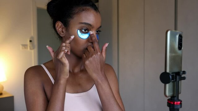 A gorgeous black African American woman is doing beauty tutorial in her room using her mobile phone