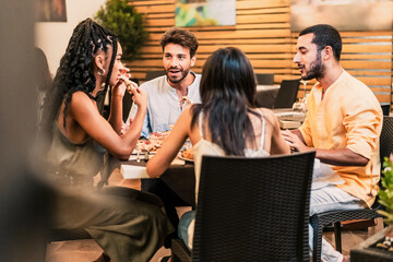 Diverse group of friends - enjoying dinner and conversation at a restaurant, sharing a meal in a...