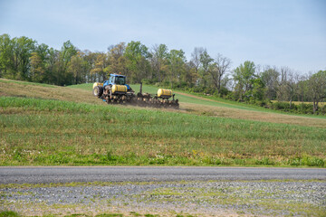 Tractor pulls planter with fertilizer tanks planting farm field
