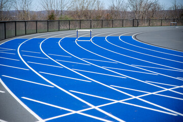 A hurdle on a fresh New athletic track background blue and gray with surface texture and crisp white lane lines sports background