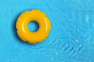 Yellow ring floating in refreshing blue swimming pool.