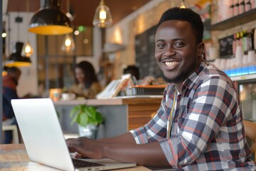 Cheerful African Man Working on Laptop in a Cozy Cafe, Showcasing Modern Remote Work Lifestyle