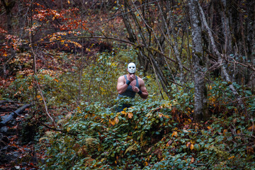 Scary Muscular Man in Mask in Autumn Forest