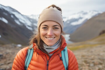 Portrait of a smiling woman in her 30s wearing a thermal fleece pullover in snowy mountain range