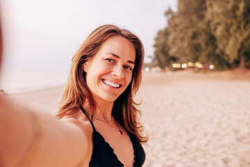 Portrait of smiling mature woman taking selfie at beach