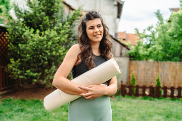 Obraz premium One young caucasian woman is carrying yoga mat preparing for training 