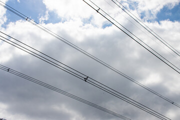Photo of an electronic pylon wires on a blue sky day with a few clouds in the sky