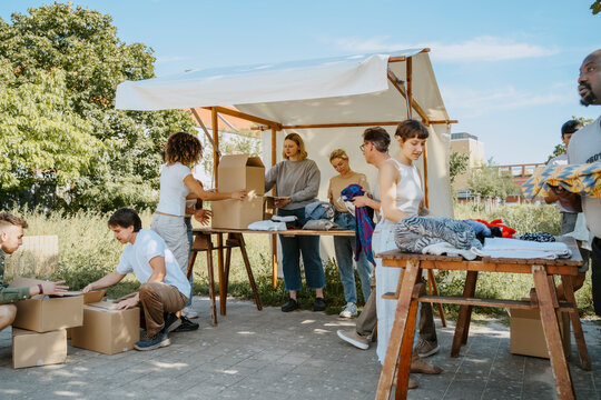 Group of multiracial volunteers arranging clothes on table during charity drive at community center
