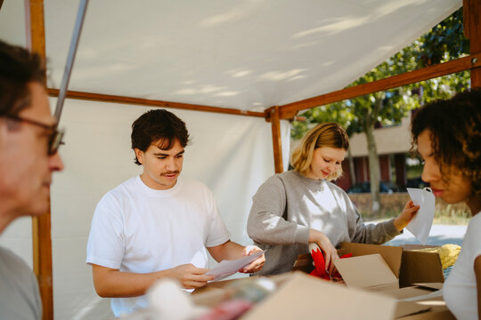 Group of multiracial volunteers labeling boxes during charity program at community center
