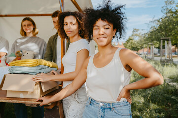 Portrait of confident female volunteers posing with team during charity drive at community center