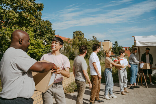 Group of multiracial male and female volunteers passing donation boxes during charity program at community center