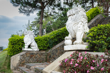 Lion statues. Two marble lions sit on a staircase on pedestals in front of the public park in Da Lat Vietnam