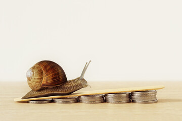 Snail climbing pile of coins - Concept of slow economic growth