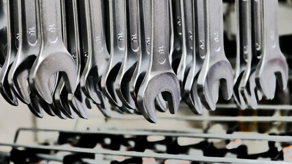 Many different sizes wrenches hanging on a store stand close-up