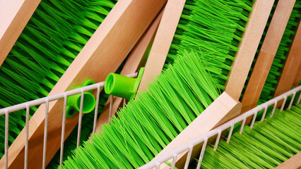 Close-up of many wooden cleaning brushes with green bristles