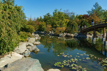 Scenic  pedestrian bridge over the large lake Oike in Japanese garden. Public landscape Galitsky...