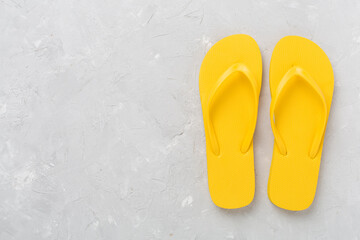 Bright yellow flip-flops on concrete background, top view. Summer concept