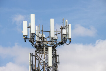 Photo of a mobile telephone communications tower on a sunny summers day with white clouds in the sky