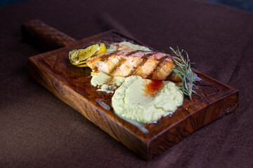 Grilled salmon fillet with lemon and herb butter on a wooden board