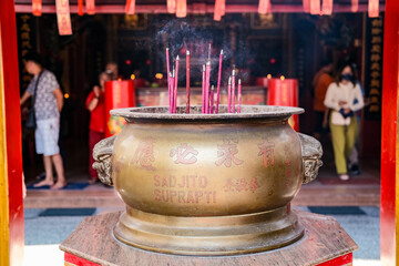 A large brass incense burner with burning sticks releases smoke in a Chinese temple at Jakarta’s...