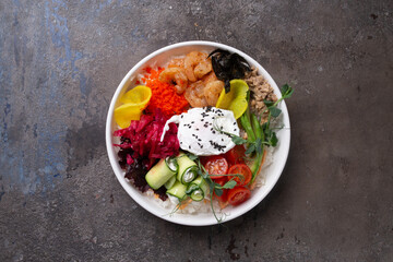 Scrumptious seafood rice bowl with fresh vegetables and egg on a dark background top view