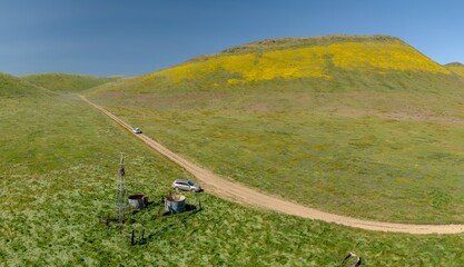 Abandoned and broken windmill and water well. Sitting in a field covered in yellow spring superbloom flowers. Carrizo National Monument, Santa Margarita, California, United States of America.