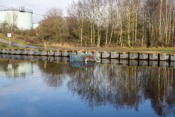 A sunken boat in a canal in the winter time in the City of Leeds in West Yorkshire in the autumn time