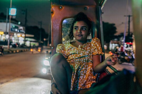 Girl looking away while traveling from tuk-tuk at night on vacation in city