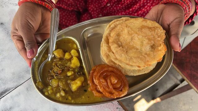 Close up shot of puri bhaji served with potato curry along jalebi at a bihari shop at daytime.